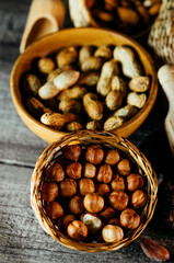 Handmade wicker baskets and wood plates with almonds, hazelnut, walnut. Vintage food background with different nuts and baskets.