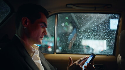 Nervous manager using smartphone in car closeup. Man looking rain drops window