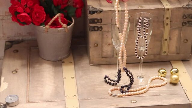 Female hand touch beads in wine glasses on wooden chest