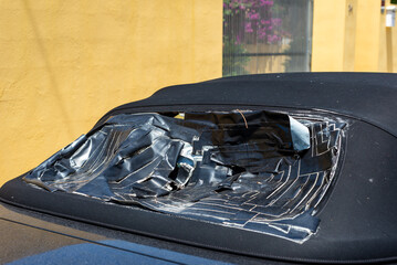 Closeup of a broken convertible rear window repaired with black duct tape