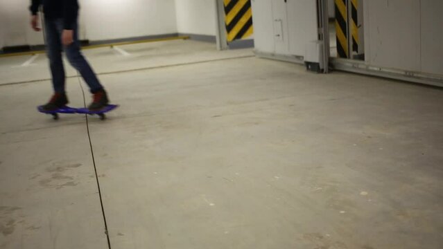 Legs of teen riding on waveboard in underground parking