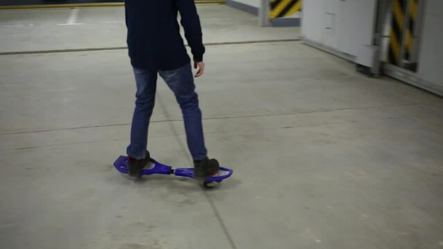 Legs of boy riding on waveboard in underground parking