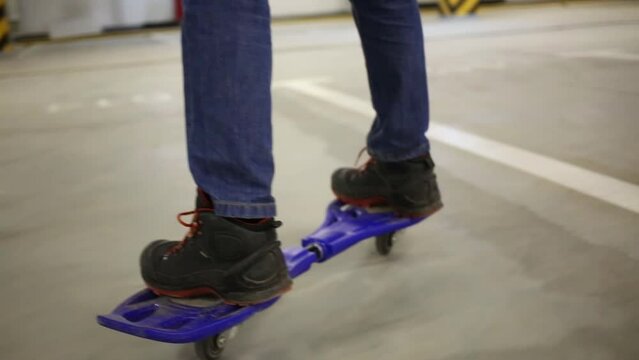 Closeup of teen feet riding on waveboard in underground parking