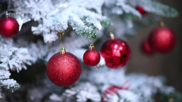 man is touching red balls which hanging on the artificial fir