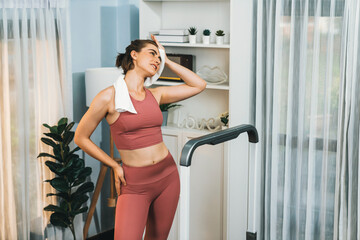 Fototapeta na wymiar Athletic and sporty woman running on treadmill running machine during home body workout exercise session for fit physique and healthy sport lifestyle at home. Gaiety home exercise workout training.