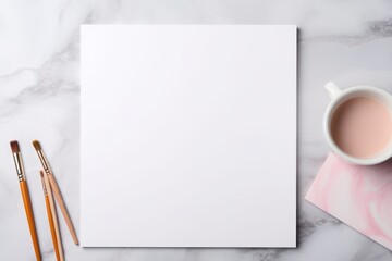 empty white paper mockup and pastel color watercolor paint brushes on the table with coffee cup flat lay. Artistic workplace template. Arts and crafts.