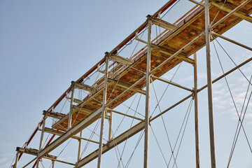 Fototapeta na wymiar Rusted Roller Coaster Framework, Safety Netting, Blue Sky Perspective