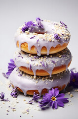 Donuts with sweet topping and  sprinkles. Decorated with purple flower petals. White background.