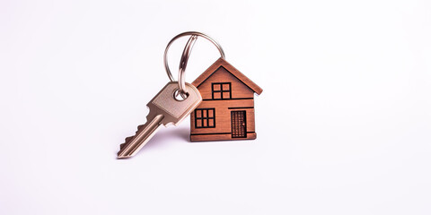 Banner with house keys with wooden keychain in house shape close-up isolated on white background for buying, renting an apartment, a house. Concept for housewarming, real estate sale, construction
