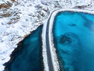 Keuken spatwand met foto Aerial view of snowy road to the island and blue sea on both side. Bridge on snow and azure transparent water in winter. Landscape. Top drone view of road to the Henningsvaer, Lofoten islands, Norway © den-belitsky