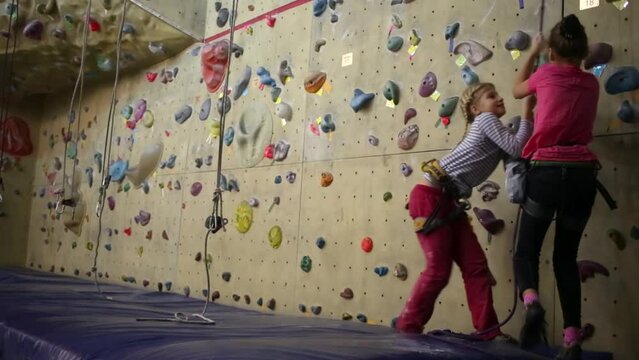 Two girls pulling a safety rope next to the climbing wall