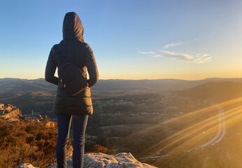 Person on the top of a mountain. Woman looking at the sunset over the blue mountains, Australia, NSW. Spectacular view from a lookout. Hiking to see the sunrise over a grand canyon. - obrazy, fototapety, plakaty