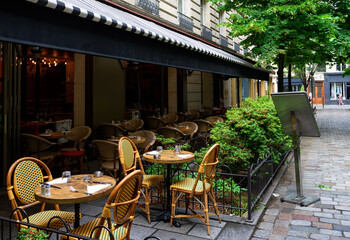 Cozy street with tables of cafe in Paris, France. Architecture and landmark of Paris. Cozy Paris cityscape