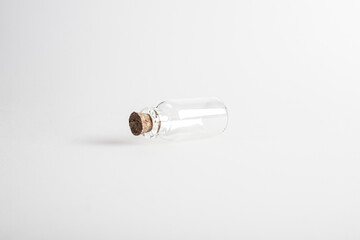 One empty mini glas bottle with closed brown cork lid laying down. The rustic and vintage jar is small and clean. It looks like an old medicin keeping. 