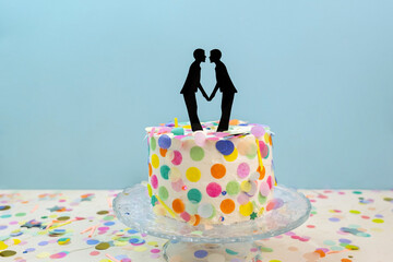 Two grooms cake toppers on decorated wedding cake. Gay wedding concept LGBTQIA