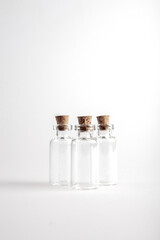 Three empty mini glas bottles with closed brown cork lid standing up. The rustic and vintage jar is small and clean. It looks like an old medicin keeping. 