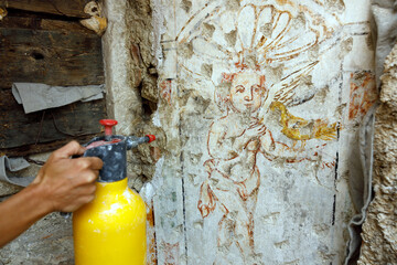 Restorer hand Wet with Water Surface of Baroque Wall Painting for Better Viewing of Faded Colors and Parts made Almost Invisible Cause Time Deterioration