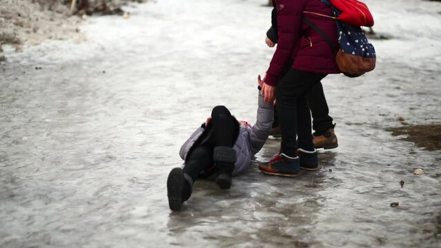 Girl goes, slips and falls down on icy surface, friends help her 