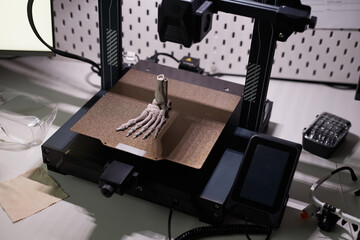 Human foot bone model on aluminum print bed of 3D printer on dim light desk with engineering...