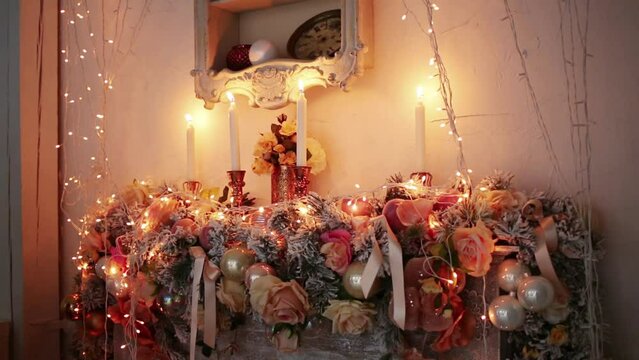 Decoration with a burning candles and many artificial flowers.