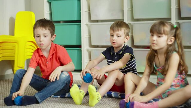 Children take the massage ball with their feet and hold it. Fun mobile games during breaks for children's health. High quality 4k footage