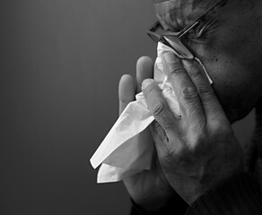 cold and flu blowing nose after catching the flu with grey black background with people stock image stock photo	
