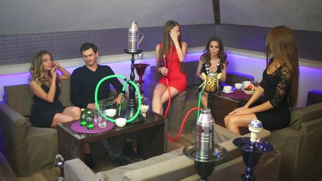 Five young people relaxing together and smoking hookah
