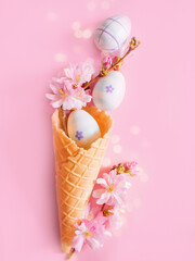 Easter background. Easter eggs, cherry blossom flowers, ice cream cone on pink background. Church...
