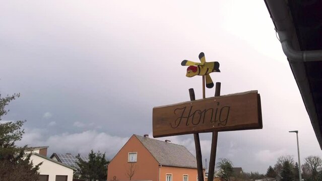 Ein Windspiel in Form einer Biene über dem Schild mit der Aufschrift Honig
