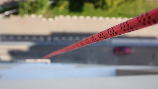 Close up of red rope, descending down into courtyard of building.