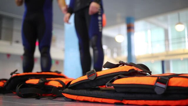 Life jackets lie on the floor by the pool next to the two men