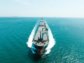 Aerial top view of cargo maritime ship with contrail in the ocean ship carrying container and...