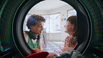 Teenage friends listening music in laundry room closeup. Smiling couple washing