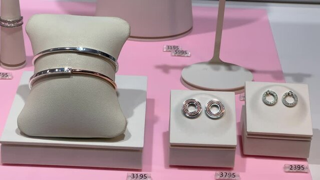Bracelets and earrings made of white and rose gold on a jewelry store display