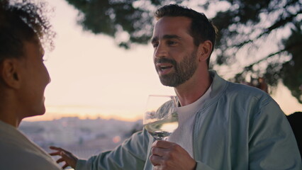 Carefree friends talking at sundown viewpoint closeup. Man drinking white wine