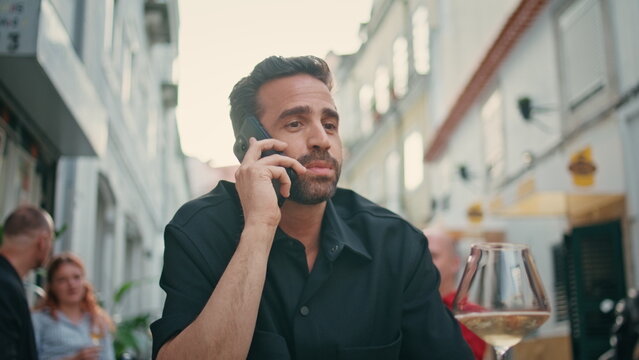 Emotional tourist talking smartphone at city bar closeup. Man with alcohol glass