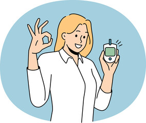 Smiling young woman holding sugar blood test monitor showing all right hand gesture. Happy healthy female satisfied with glucose level. Healthcare concept.