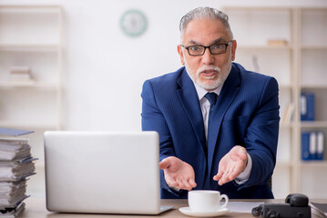 Old male employee drinking coffee during break