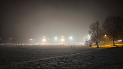 The soccer field is lit up in the fog