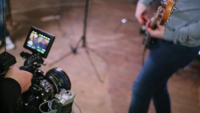 Operator shots guitarist with professional camera equipment in studio