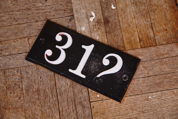 Vintage Number 312 Address Plaque on Textured Wooden Floor