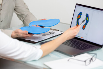 Doctor consulting male patient on custom orthotic insoles in a clinic for a personalised custom...