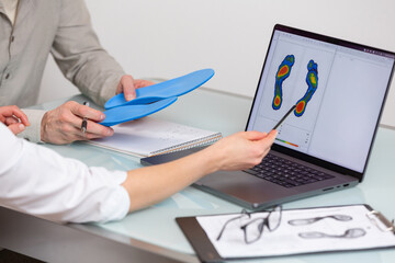 Doctor consulting patient on custom orthotic insoles in a clinic for a personalised custom fit. Feet recreation medicine concept - 718339952