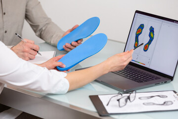 Doctor consulting patient on custom orthotic insoles in a clinic for a personalised custom fit. Feet recreation medicine concept - 718339985