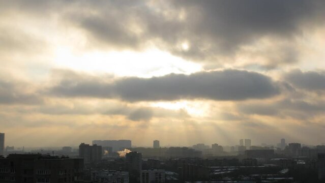 Winter town with chimneys, the suns rays make way through the clouds