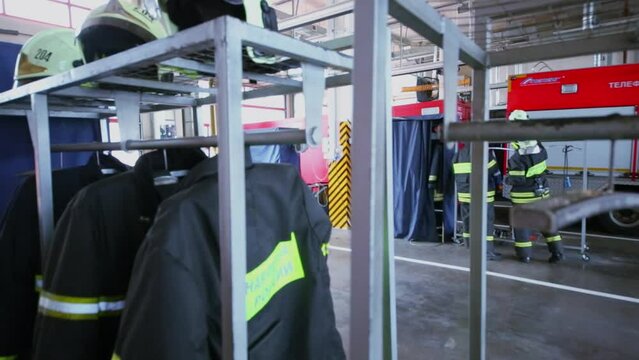 Garage with fireproof suits and firemen near walk truck