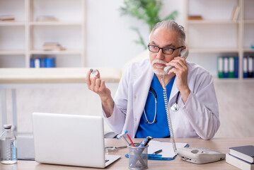 Old male doctor in telemedicine concept
