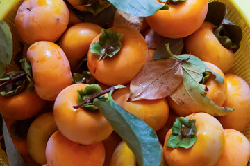 Ripe persimmons in a basket on a wooden table.
