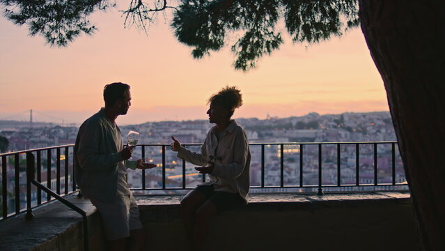 Carefree couple dating on evening viewpoint at sunset. Dark silhouettes people