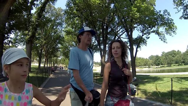 Family with daughter and son walking on sidewalk in park 